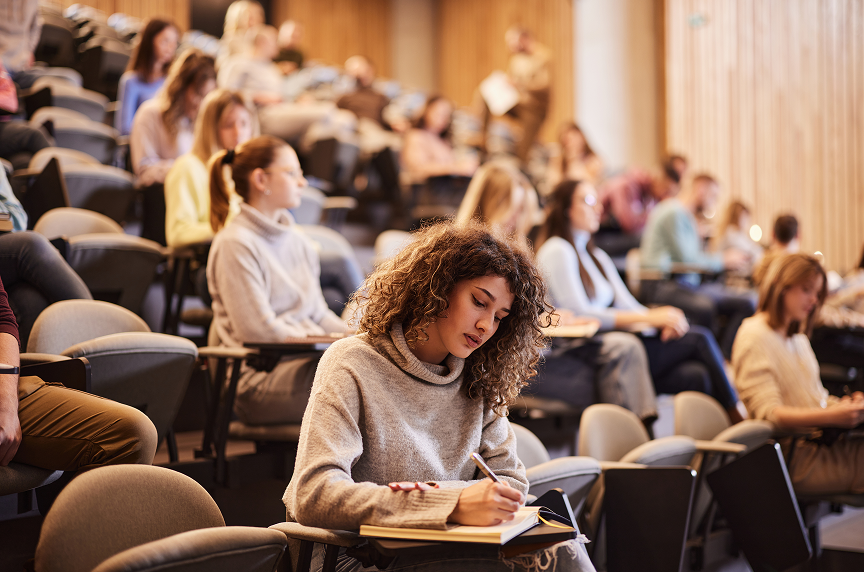 A college student in class writing down class notes