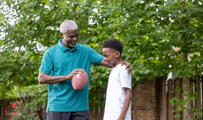 Grandpa and grandson outside playing football