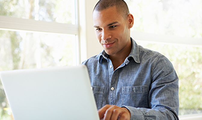 A man sitting at a table on his laptop