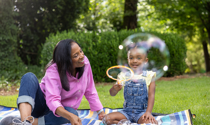 Grandma and granddaughter blowing bubbles outside