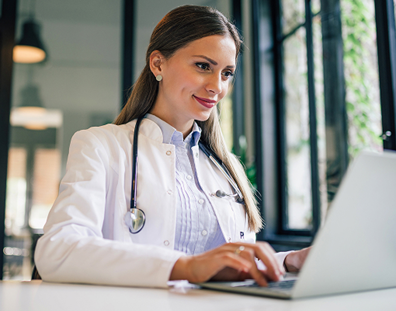 A doctor sitting at her desk typing away on her laptop