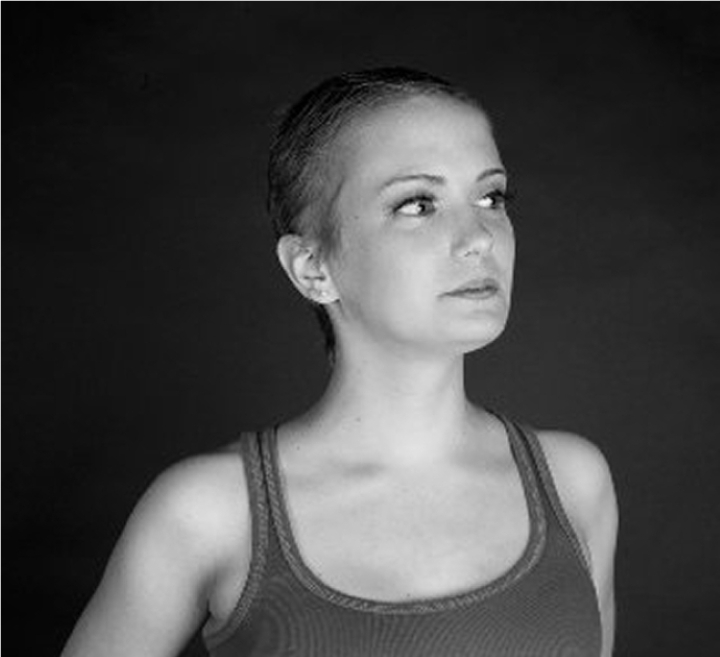 A black and white portrait of a young woman in a tank top looking thoughtfully to the side against a dark background.