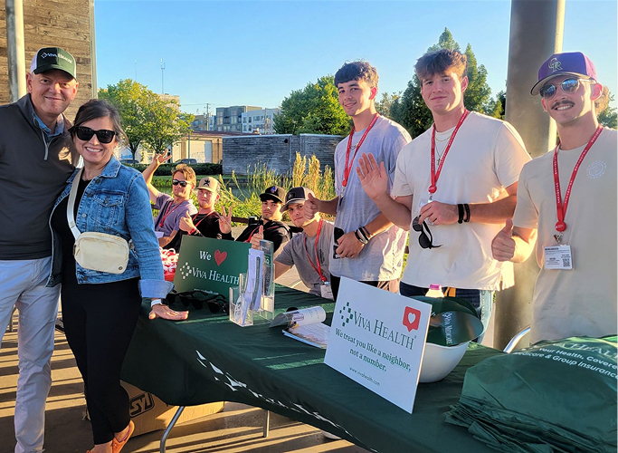 Volunteers staffing an outdoor event table with Viva Health branding.