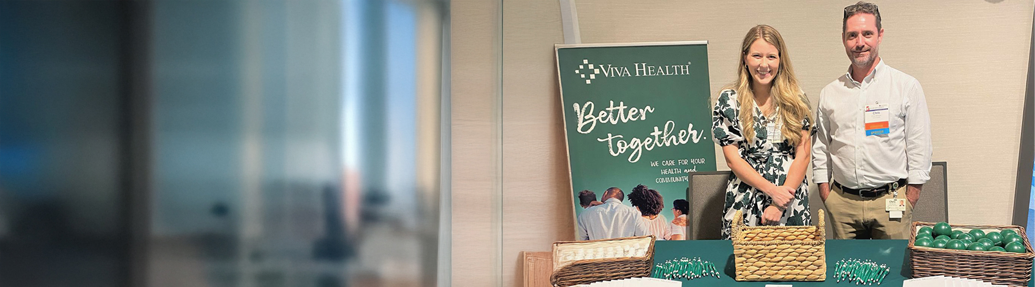 Two Viva Health employees standing behind a table with Viva Health merchandise on it