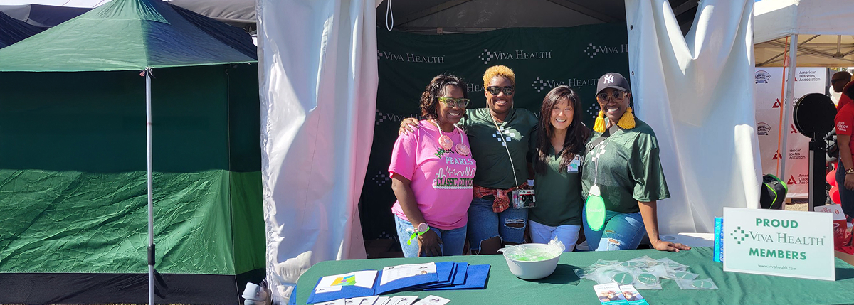 Four Viva employees standing behind a table, smiling and posing for a picture