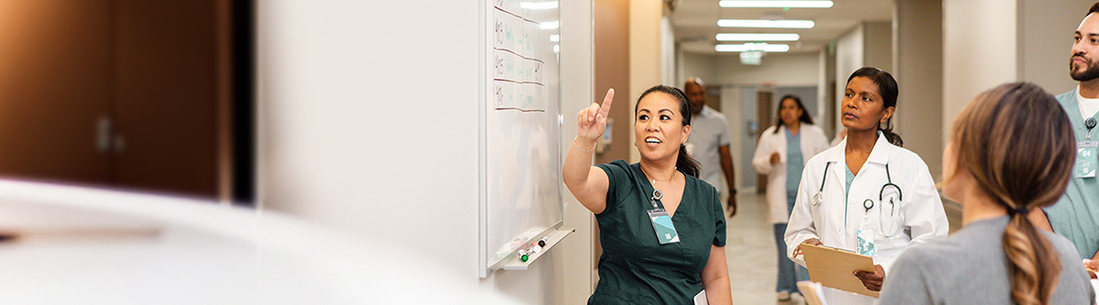 A group of nurses and a doctor in a hospital discussing information written on a white board