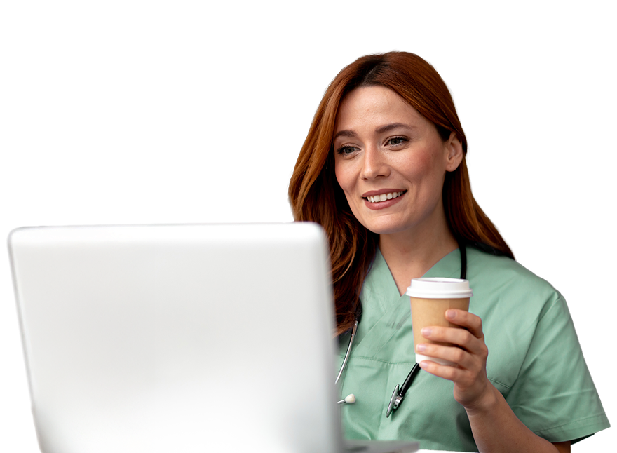 A smiling healthcare provider in green scrubs with a stethoscope, holding a cup of coffee while looking at a laptop screen.